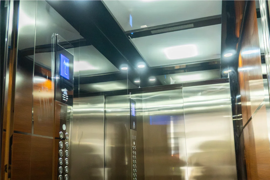 Interior de cabina de ascensor con panel y pasamanos